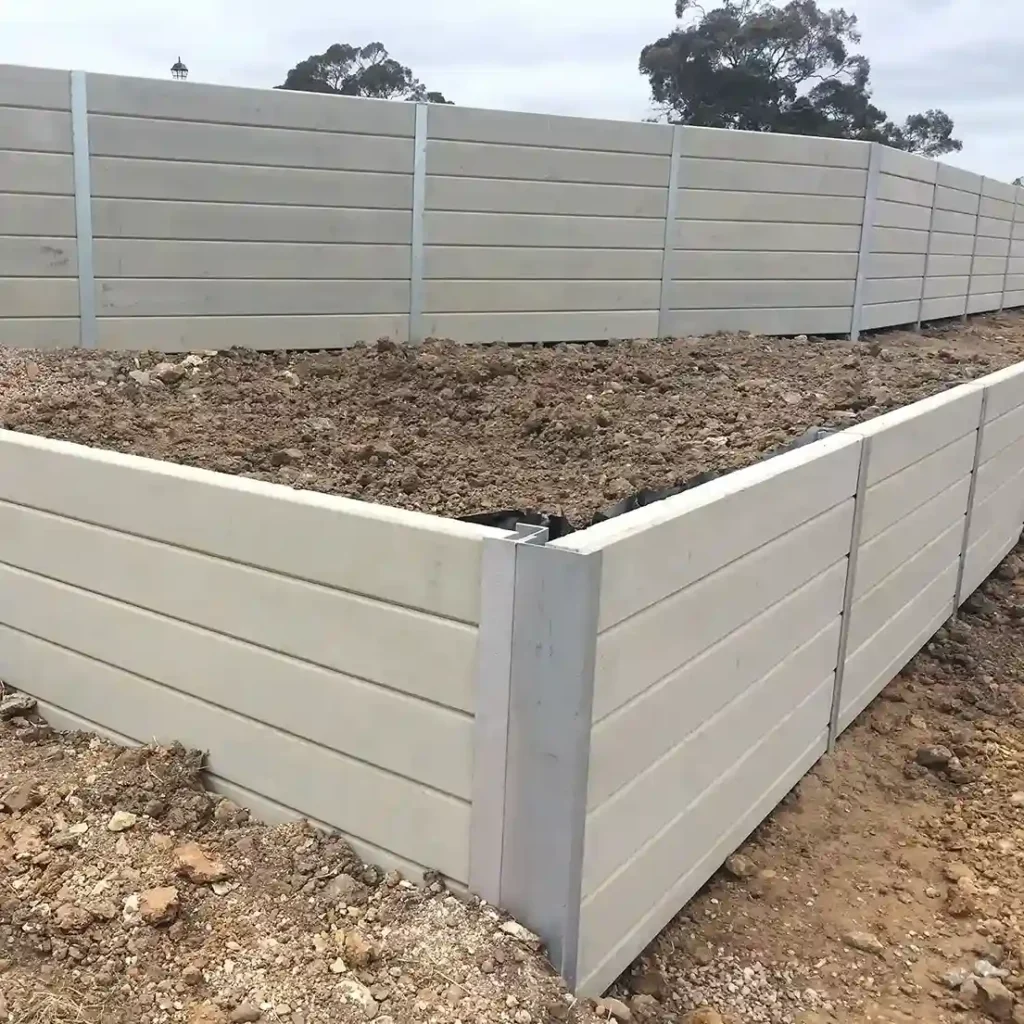 Durable concrete retaining wall under construction, supporting soil on a sloped site